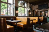 a restaurant with tables and chairs and windows at The Brewers Inn in London