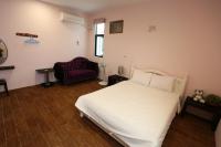 a bedroom with a white bed and a purple couch at See Your Dreams B&amp;B in Magong