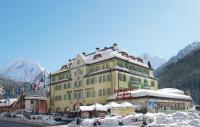 a large yellow building with snow on the ground at Hotel Dolomiti Schloss in Canazei