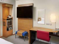 a hotel room with a desk with a tv and a bed at Novotel London West in London