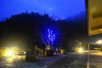 a blue lighted tree with tables and chairs at night at Zhong Ming Ju Taoyi Fang in Fanlu