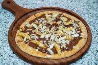 a pizza with chocolate and peanuts on a wooden plate at فندق براي Brai Hotel in Ad Dawādimī