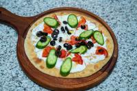 una pizza con cetrioli e olive su una tavola di legno di فندق براي Brai Hotel ad Ad Dawādimī