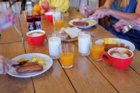 a wooden table with plates of breakfast foods and glasses of milk at Red Panda Hostel & Cafe in Chiang Mai
