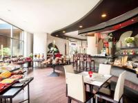 un ristorante con tavoli, sedie e un bancone di Horison Arcadia Wahid Hasyim a Giacarta