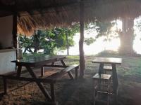 un tavolo da picnic e uno sgabello sotto una capanna di Hostel Los Chocoyos a Ometepe