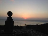 a sunset over the ocean with a statue in the foreground at Ibizakenting Hotel in Kenting