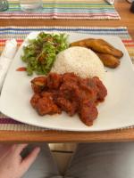 a plate of food with rice and vegetables on a table at Pito Guest House in Elmina