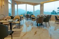 een restaurant met tafels en stoelen en grote ramen bij The Barns Resort in Bhīm Tāl