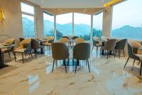 een restaurant met tafels en stoelen en grote ramen bij The Barns Resort in Bhīm Tāl