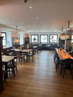 a dining room with tables and chairs and windows at Hotelgasthof Kirchenwirt in Schierling