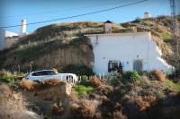 a white car parked in front of a house on a hill at Cueva La Loli in Guadix