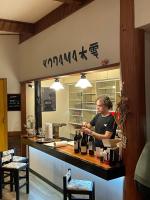 a man standing behind a counter with bottles of wine at Kodama Lodge in Otari