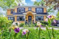 a yellow house with purple flowers in front of it at The Stella Rose B&amp;B in Wolfville