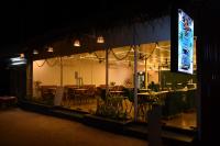 a restaurant with tables and chairs and a large screen at Escape Goa in Palolem