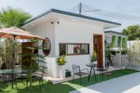 una casa blanca con una mesa y sillas y una sombrilla en Space Water House พูลวิลล่าครอบครัว, en Ban Pong