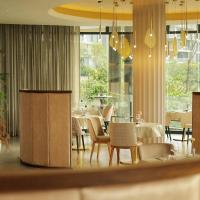 Un comedor con mesas y sillas y ventanas. en The Houghton Hotel, Spa, Wellness & Golf, en Johannesburgo