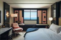 a bedroom with a bed and a chair and a window at Hotel Renew in Honolulu