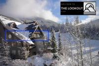una casa cubierta de nieve con una montaña en el fondo en THE LOOKOUT PENTHOUSE &#47;&#47; a luxe suite in Whistler, en Whistler