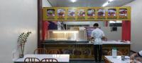 Un hombre está preparando comida en la cocina de un restaurante. en SID'S Traveller's INN, en General Santos