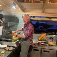 Ein älterer Mann steht in einer Küche und bereitet Essen vor. in der Unterkunft The Red Lion in Blewbury