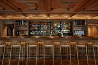 a bar with stools in a room with wooden ceilings at Miiro The Mansard in Gstaad