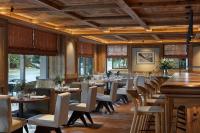 a restaurant with wooden ceilings and tables and chairs at Miiro The Mansard in Gstaad