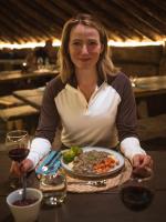 una mujer sentada en una mesa con un plato de comida en Eventyrhyttene i Jotunheimen, en Stuttgongfossen