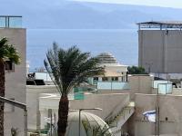 eine Palme vor einem Gebäude mit dem Meer in der Unterkunft shohamseaview in Eilat