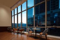 um quarto com mesas e cadeiras e janelas grandes em 深圳南山万象青华酒店 em Shenzhen