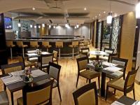 a restaurant with tables and chairs and a bar at Nash Suites Airport Hotel in Geneva