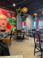 een restaurant met tafels en stoelen en een schilderij van een vrouw bij The Taksim Patong Beach Hotel in Patong Beach