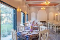 uma sala de jantar com mesas e cadeiras e uma grande janela em JuSTa Alwarbagh Sariska em Alwar