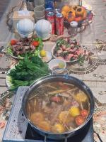 een tafel met een pot soep en borden eten bij Homestay Núi Đá Tả Phìn in Sa Pa