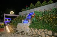 a garden with flowers and a stone wall at night at Fuego Hotel in Kampala