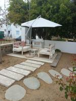 a patio with a table and an umbrella and benches at Theofanis Studios in Agia Anna Naxos