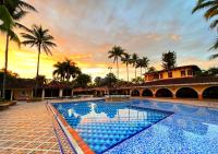 Una gran piscina con una puesta de sol al fondo en Tequendama Hotel Campestre Villavicencio, en Villavicencio