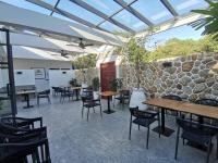 Un patio con mesas y sillas y un muro de piedra. en Skye Beach Koh Samui, en Choeng Mon Beach