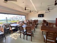 VengurlaBaywatch Resort Bhogave Beach的一家餐厅，里面有桌椅和一个大窗户。