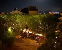 Un grupo de personas sentadas en un banco en un jardín por la noche. en Hôtel La Petite Bohème, en Le Lavandou