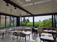 Un restaurante con mesas y sillas y grandes ventanales. en Hôtel La Petite Bohème, en Le Lavandou