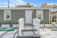 ein graues Haus mit einer weißen Tür und einigen Pflanzen in der Unterkunft Cozy Beachside Bungalow Studio Ideal for Couples in Myrtle Beach