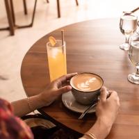 una persona sosteniendo una taza de café y una bebida en Mahagiri Villas & Spa Dreamland, en Uluwatu