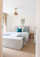 ein weißes Schlafzimmer mit einem Bett mit blauen Kissen in der Unterkunft Five Pines Studio in Woodend