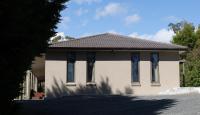 ein weißes Haus mit braunem Dach in der Unterkunft Five Pines Studio in Woodend