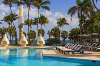 a swimming pool with chaise lounge chairs and palm trees at Renaissance Santo Domingo Jaragua Hotel & Casino in Santo Domingo