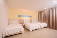 two beds in a room with white sheets at i-Deal Hotel in Taichung