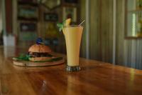 a drink sitting on a table next to a hamburger at Patrick's on the Beach Resort in General Luna