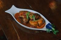 a plate of food with meat and sauce on a table at Patrick's on the Beach Resort in General Luna