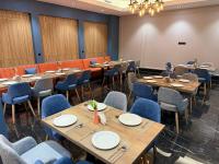 Rivana Boutique Hotel في طشقند: مطعم بطاولات خشبية وكراسي زرقاء